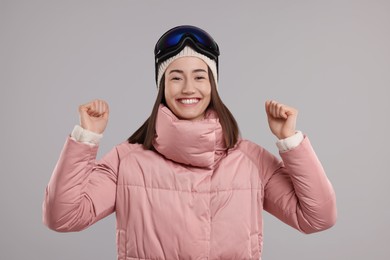 Winter sports. Excited woman with snowboard goggles on grey background