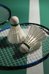 Feather badminton shuttlecocks and rackets on court, closeup