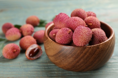 Photo of Fresh ripe lychee fruits in bowl on wooden table. Space for text