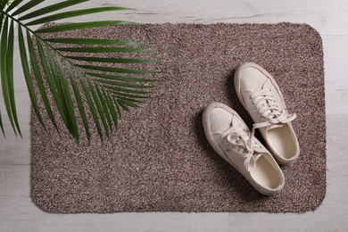 Photo of New clean door mat, shoes and plant on floor, flat lay