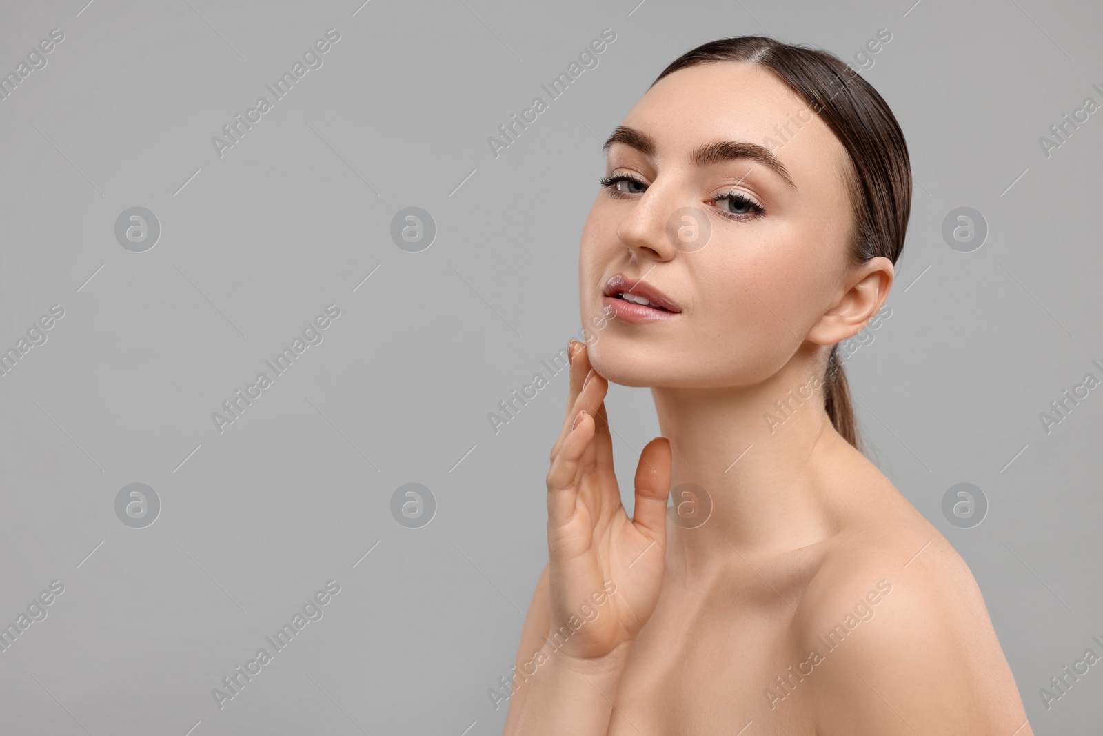Photo of Beautiful woman touching her chin on grey background. Space for text