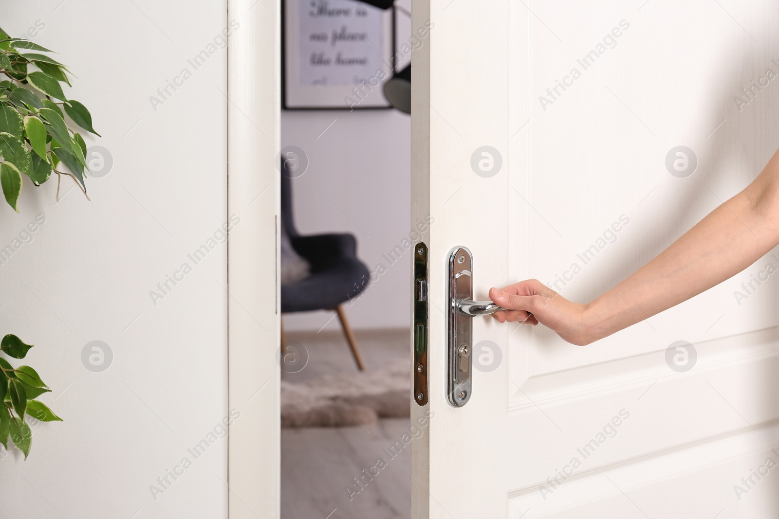 Photo of Young woman opening door to beautifully arranged room. Interior design