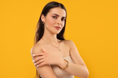 Beautiful woman with elegant jewelry on orange background