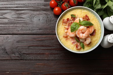 Photo of Fresh tasty shrimps, bacon, grits and basil in bowl on wooden table, flat lay. Space for text