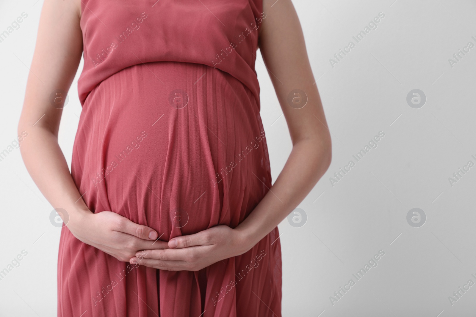 Photo of Young pregnant woman on light background, closeup. Space for text