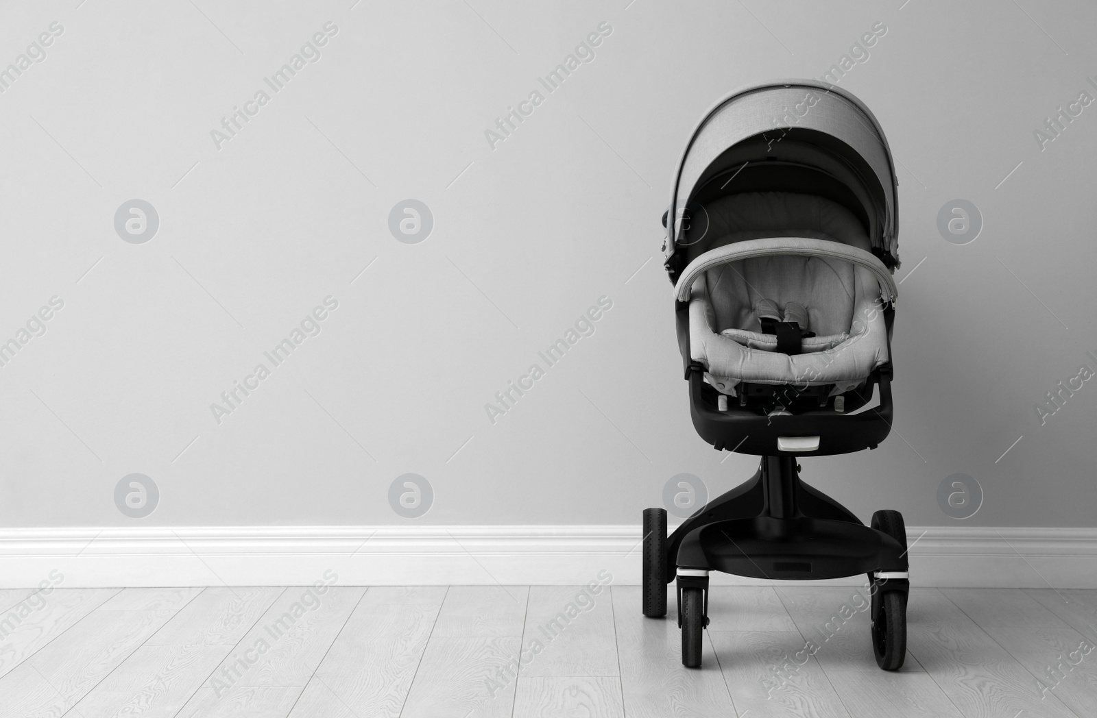 Photo of Baby carriage. Modern pram near light grey wall, space for text