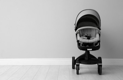 Photo of Baby carriage. Modern pram near light grey wall, space for text