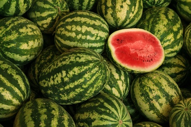 Photo of Delicious whole and cut watermelons as background, above view