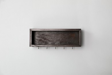 Photo of Wooden hanger for keys on light grey wall