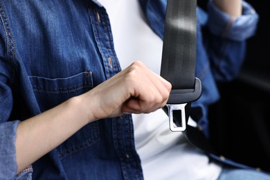 Photo of Woman fastening safety seat belt inside modern car