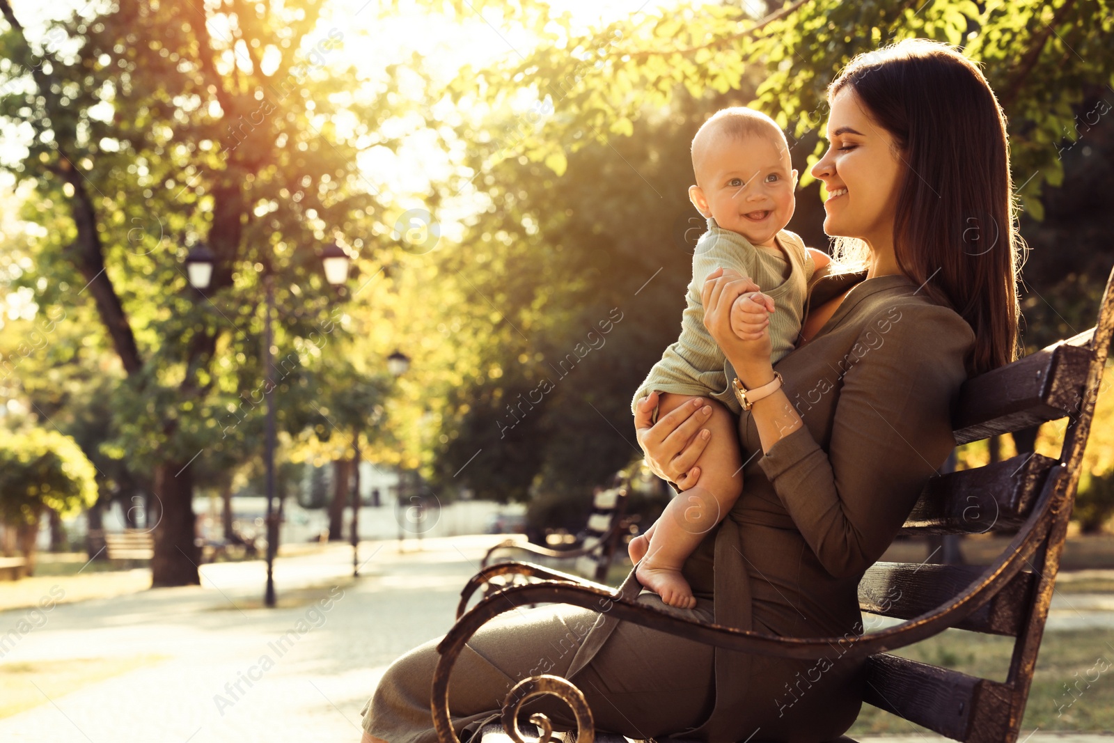 Photo of Young mother with her cute baby on bench in park