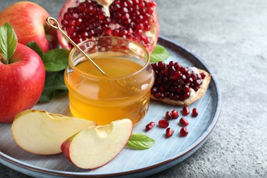 Photo of Honey, pomegranate and apples on grey table, closeup. Rosh Hashana holiday