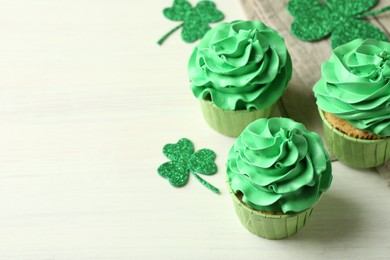 Photo of St. Patrick's day party. Tasty cupcakes with green cream on white table, closeup. Space for text