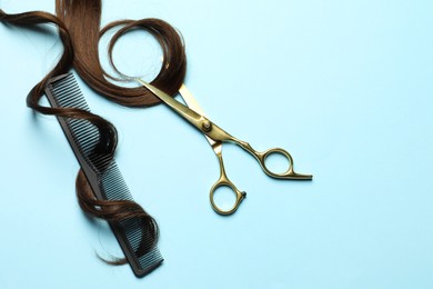 Professional hairdresser scissors and comb with brown hair strand on light blue background, flat lay. Space for text