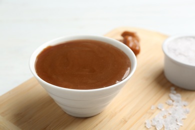 Photo of Bowl with caramel sauce and salt on board, closeup