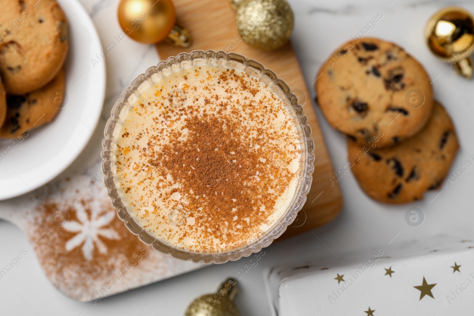 Photo of Glass of delicious eggnog with cinnamon on white table, flat lay