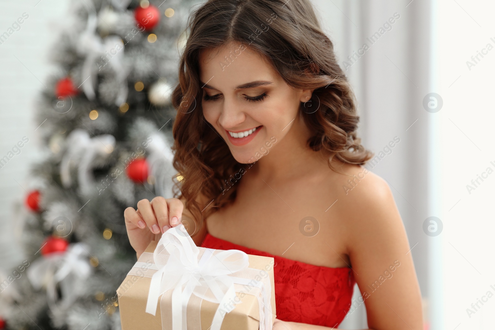 Image of Happy young woman with Christmas gift at home