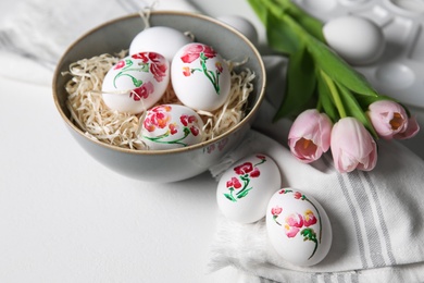 Photo of Beautifully painted Easter eggs and tulips on white table