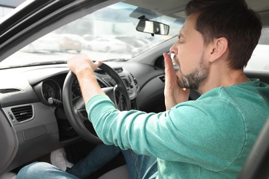 Photo of Sleepy tired man yawning in his modern car