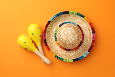 Mexican sombrero hat and maracas on orange background, flat lay