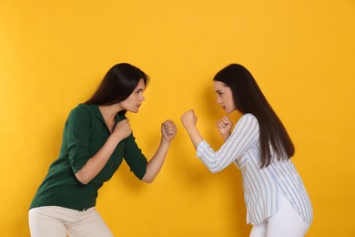 Photo of Young women ready to fight on orange background