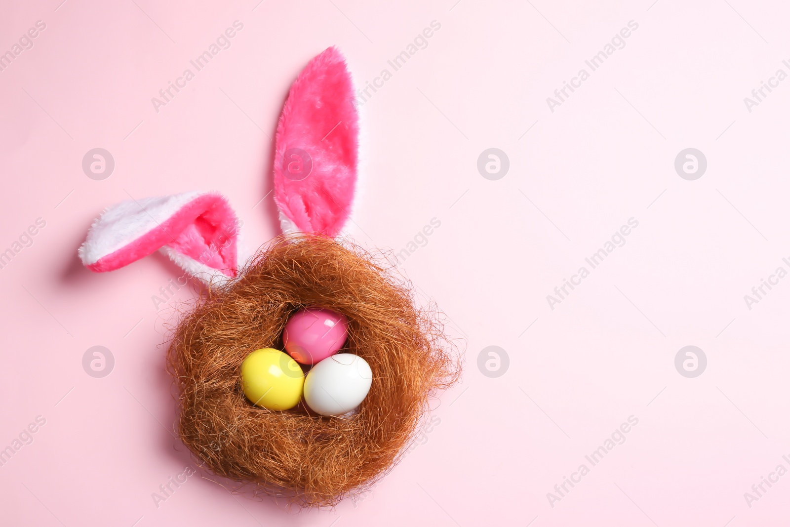 Photo of Flat lay composition of Easter bunny ears with eggs on color background, space for text