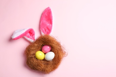 Photo of Flat lay composition of Easter bunny ears with eggs on color background, space for text