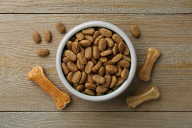 Dry dog food and treats (chew bones) on wooden floor, flat lay