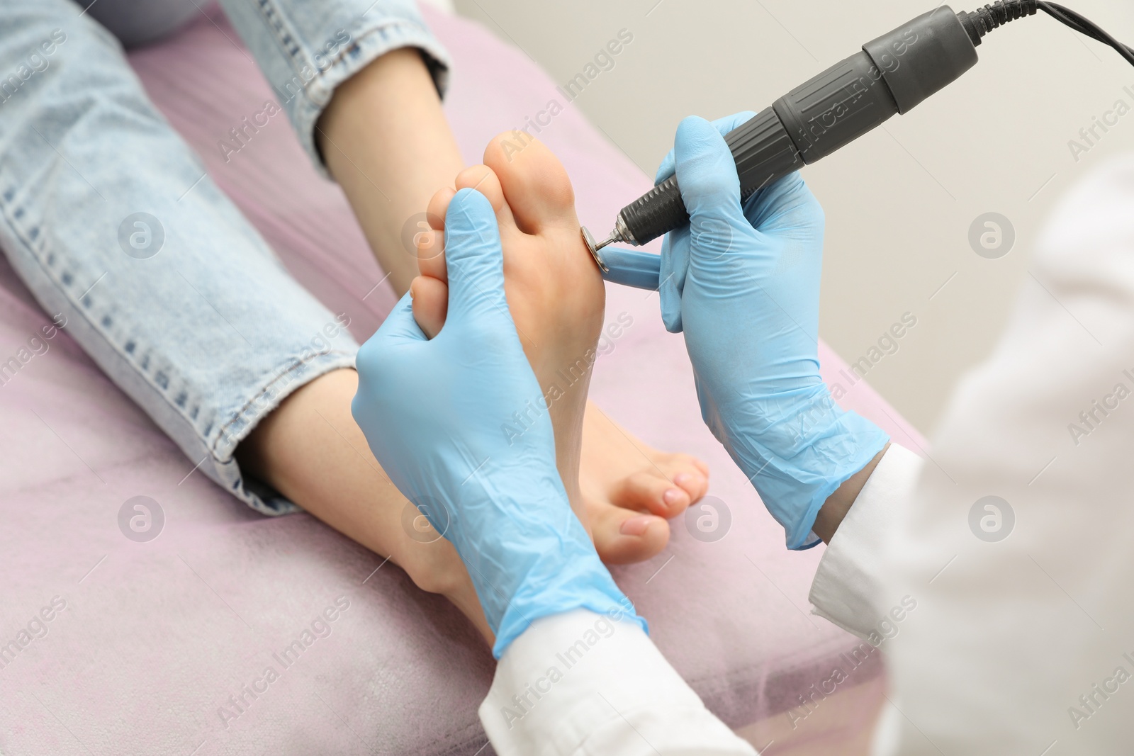 Photo of Professional master making hardware pedicure for client in beauty salon, closeup