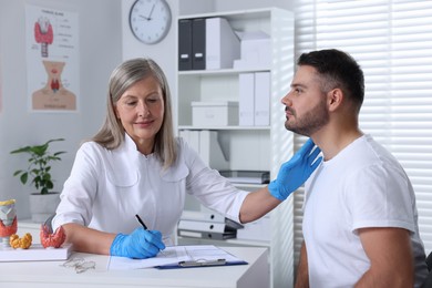 Photo of Endocrinologist examining thyroid gland of patient at table in hospital