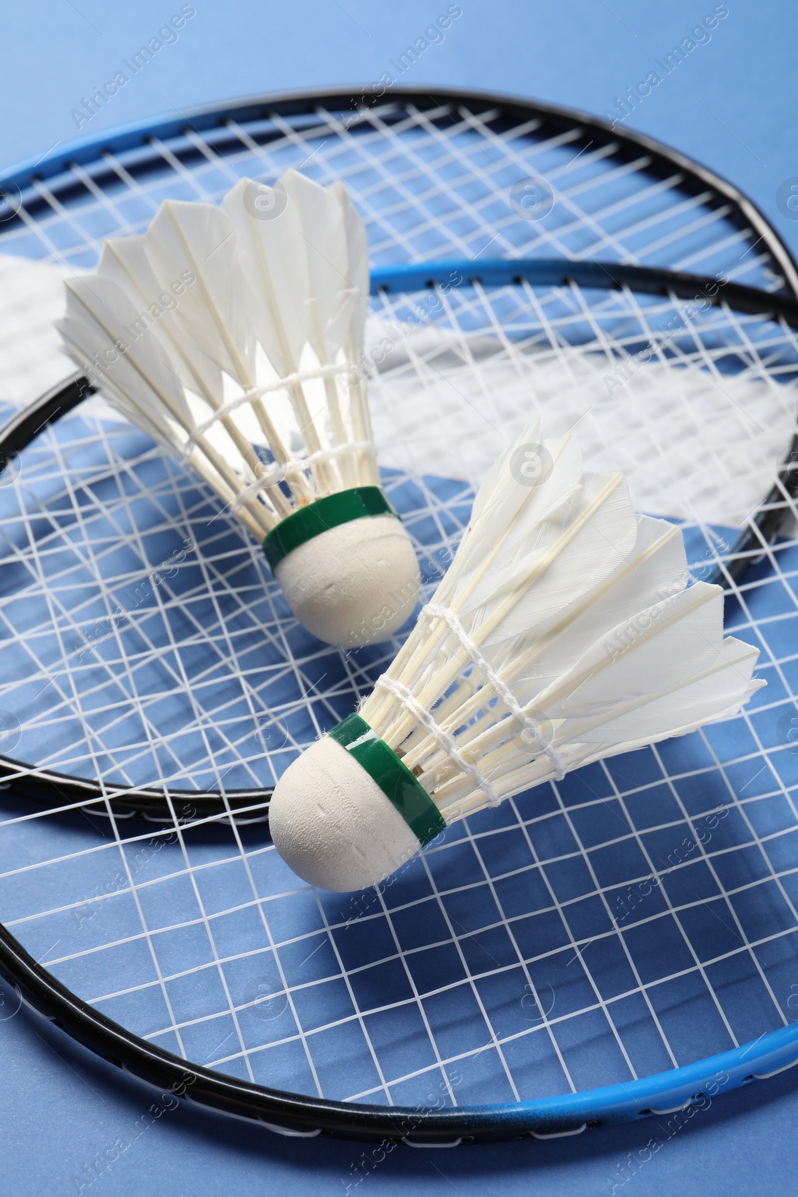 Photo of Feather badminton shuttlecocks and rackets on blue background, closeup