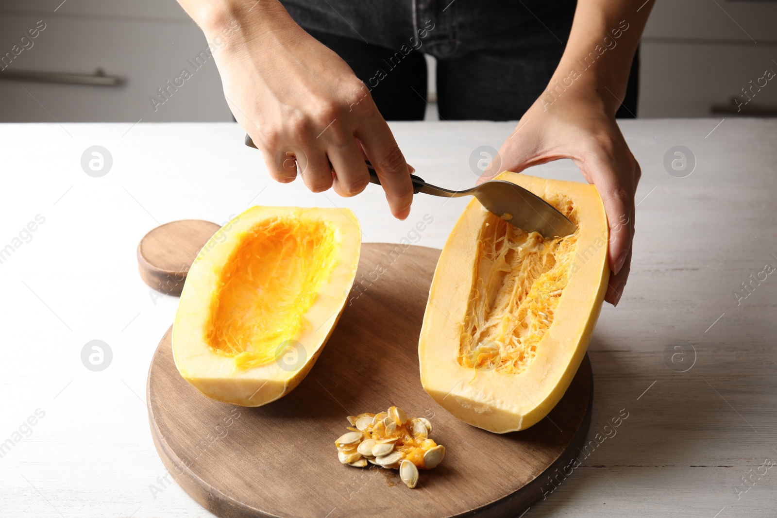 Photo of Woman removing seeds from spaghetti squash on table, closeup