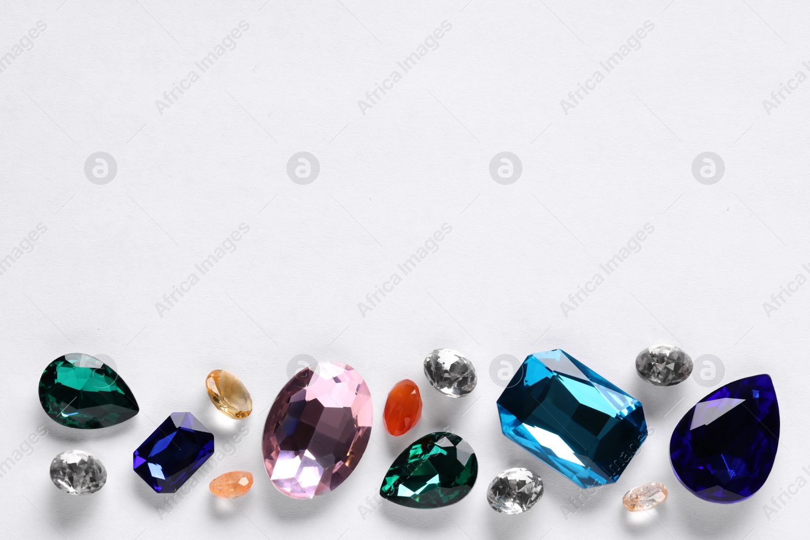 Photo of Different beautiful gemstones for jewelry on white background, top view. Space for text