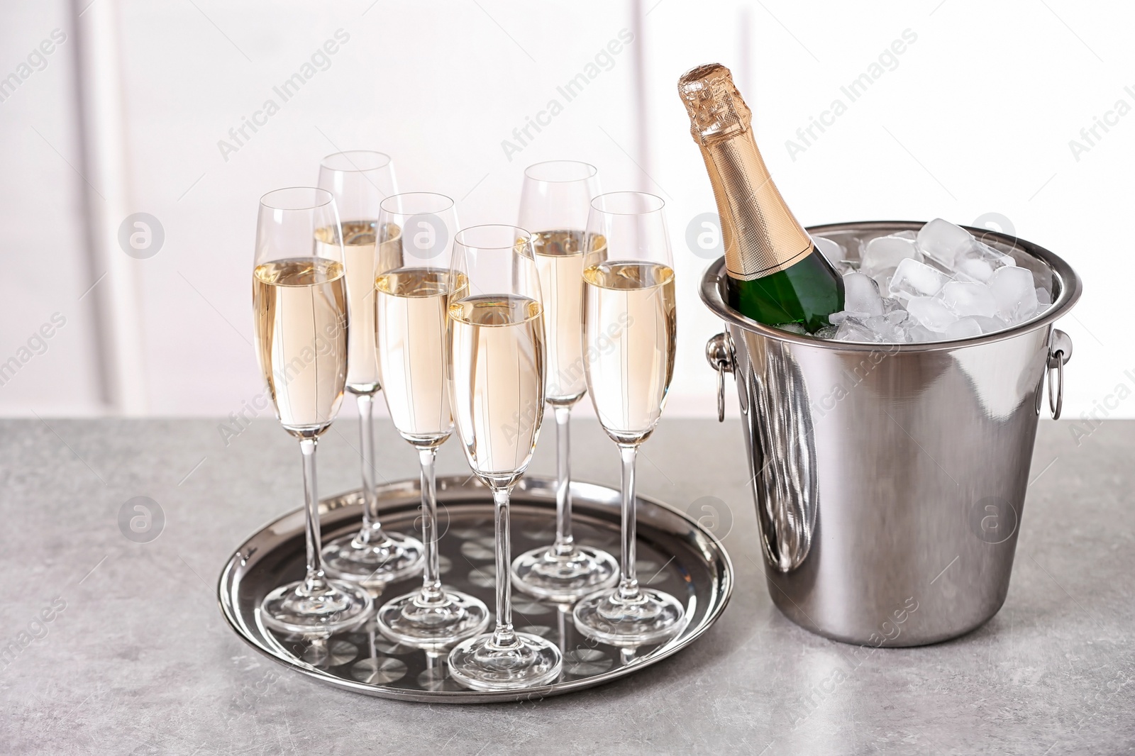 Photo of Glasses with champagne and bottle in bucket on table indoors