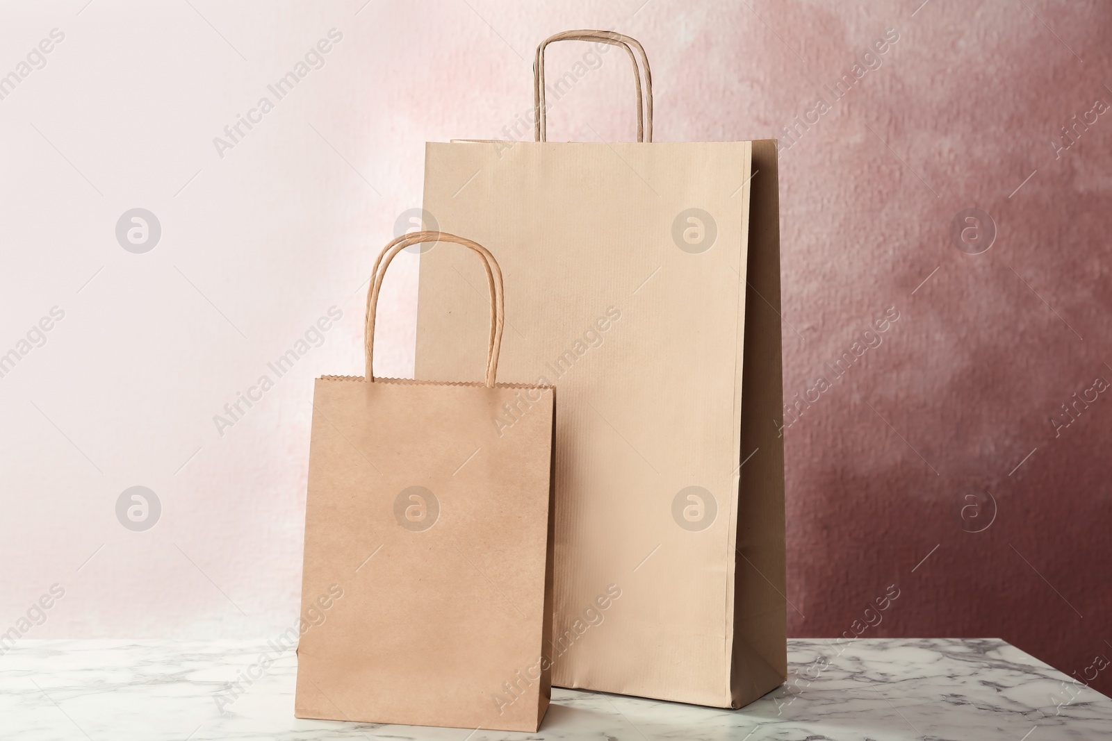 Photo of Mockup of paper shopping bags on table against color background