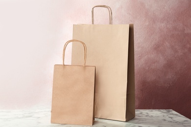 Photo of Mockup of paper shopping bags on table against color background