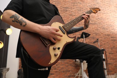 Photo of Man playing electric guitar during rehearsal in studio, closeup. Music band practice