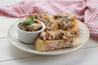 Photo of Tasty sandwiches with cod liver and parsley on white wooden table