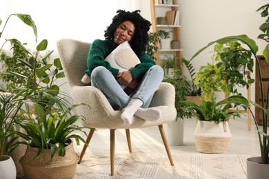 Photo of Woman relaxing surrounded by beautiful houseplants at home