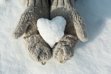 Photo of Woman holding heart shaped snowball outdoors, top view