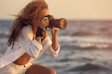African American photographer taking photo with professional camera near sea