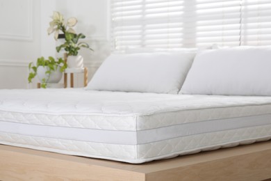 Wooden bed with soft white mattress and pillows indoors