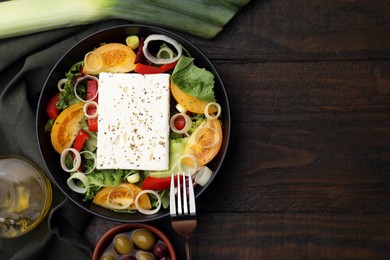 Photo of Bowl of tasty salad with leek, cheese and olives served on wooden table, flat lay. Space for text
