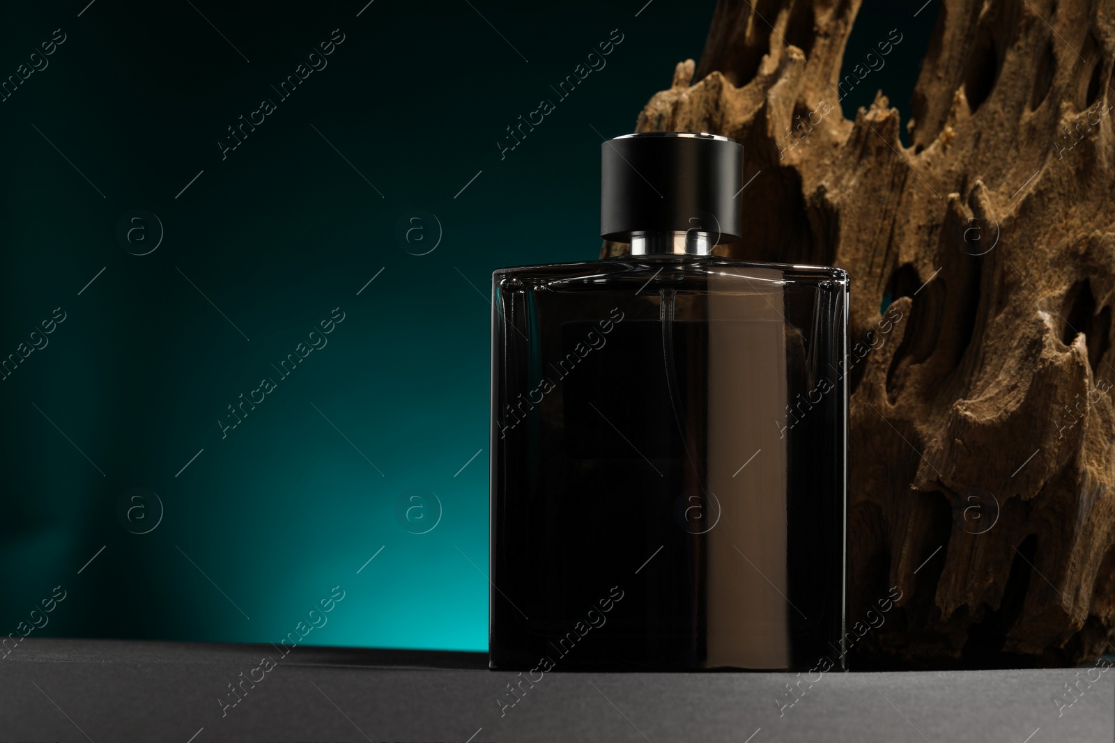 Photo of Luxury men`s perfume in bottle on grey table against color background, space for text