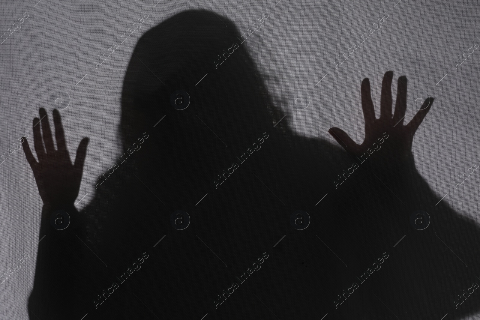 Photo of Silhouette of creepy ghost behind grey cloth