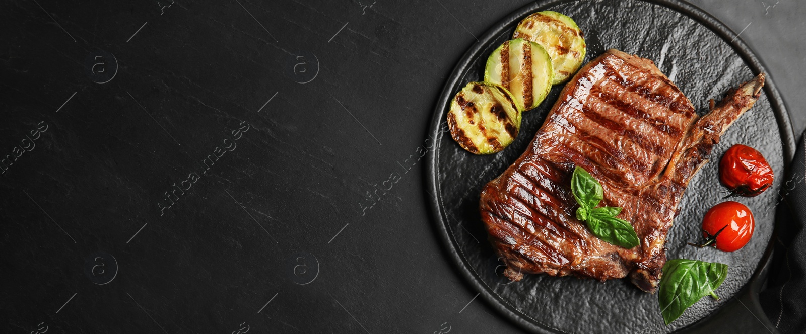 Image of Slate plate with grilled meat steak and space for text on black table, top view. Banner design