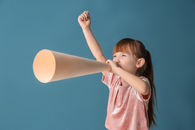 Photo of Cute little girl with paper megaphone on color background