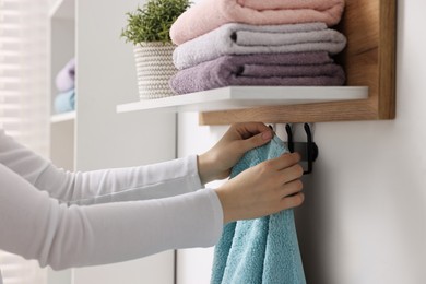 Photo of Woman hanging clean towel indoors, closeup view