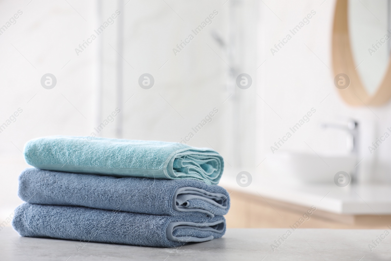 Photo of Stack of fresh towels on table in bathroom. Space for text