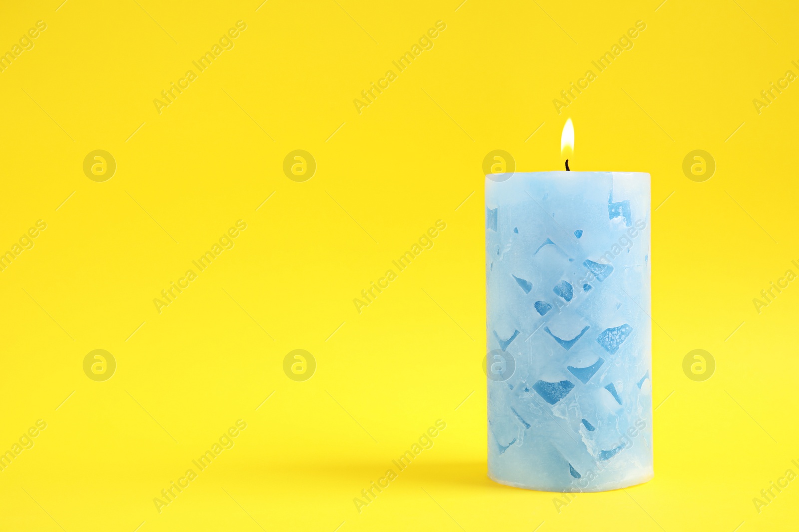 Photo of Alight wax candle on color background. Space for text